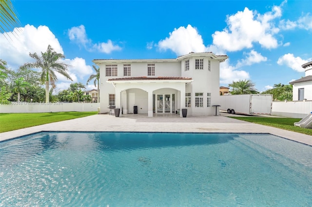 rear view of house featuring a yard, a patio area, a fenced in pool, and french doors