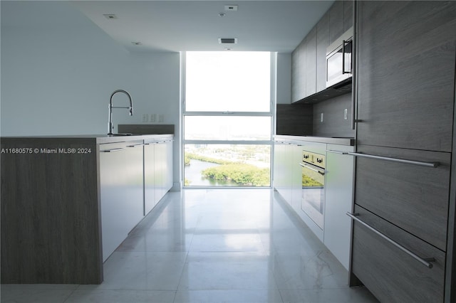 kitchen with a wall of windows, white cabinets, and fridge