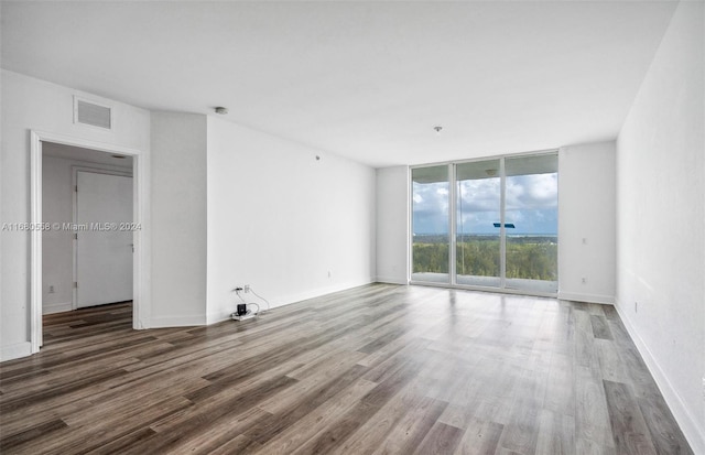 spare room with a wall of windows and hardwood / wood-style flooring