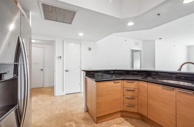 kitchen with sink, dark stone counters, and stainless steel refrigerator