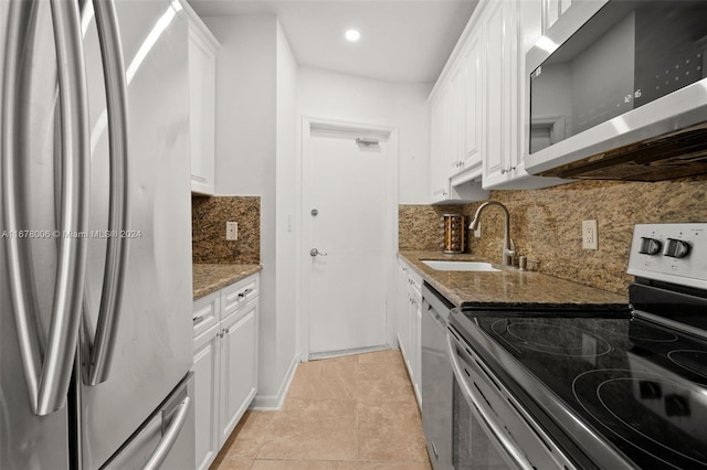 kitchen with light tile patterned floors, white cabinetry, stone countertops, sink, and stainless steel appliances