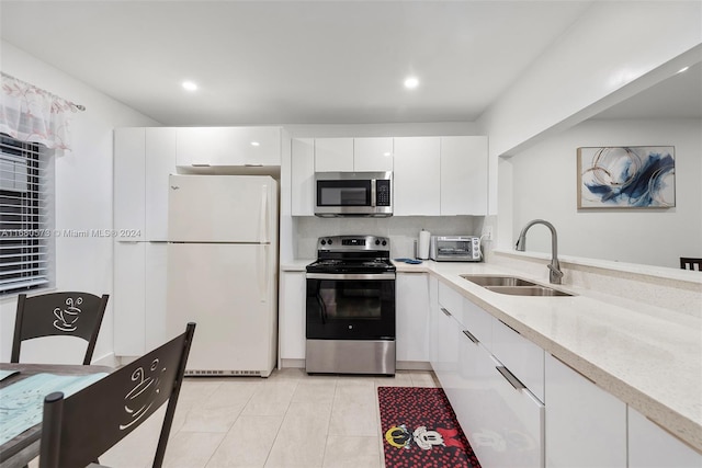 kitchen featuring light stone countertops, appliances with stainless steel finishes, sink, white cabinets, and light tile patterned floors