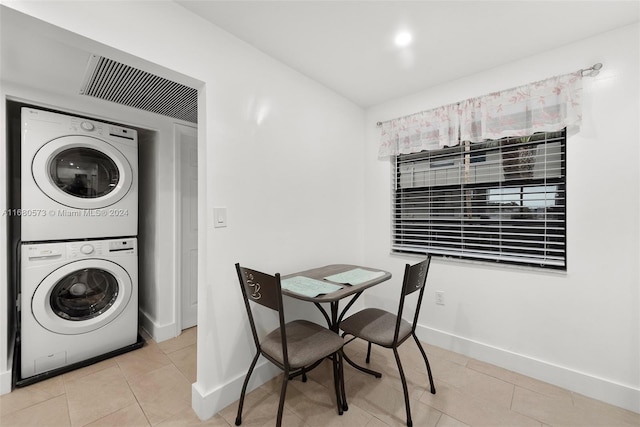 laundry room featuring stacked washing maching and dryer and light tile patterned floors