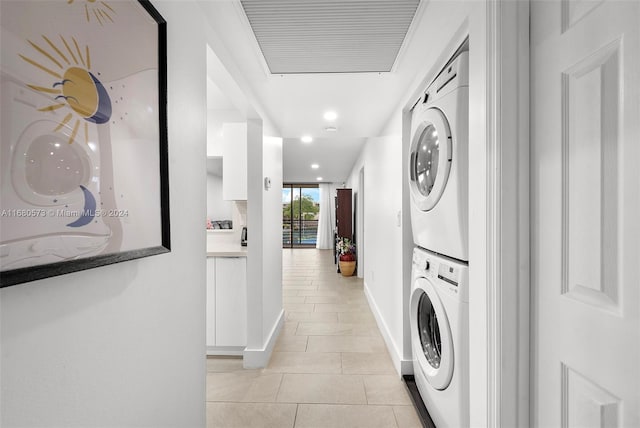 washroom with light tile patterned flooring and stacked washer and dryer