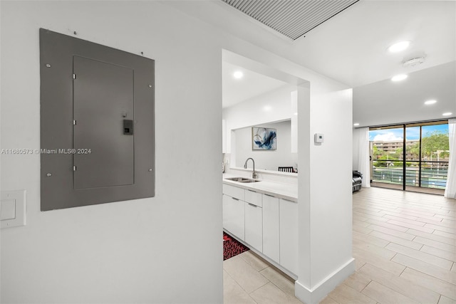 kitchen with white cabinetry, electric panel, sink, and floor to ceiling windows