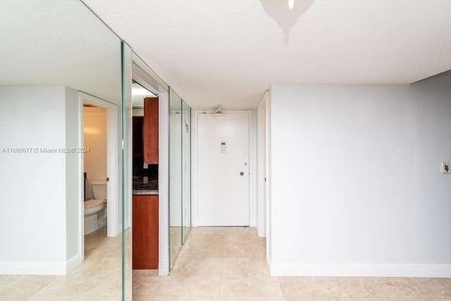 hall featuring a textured ceiling and light tile patterned floors