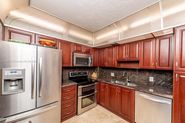 kitchen with dark stone countertops, backsplash, stainless steel appliances, and sink