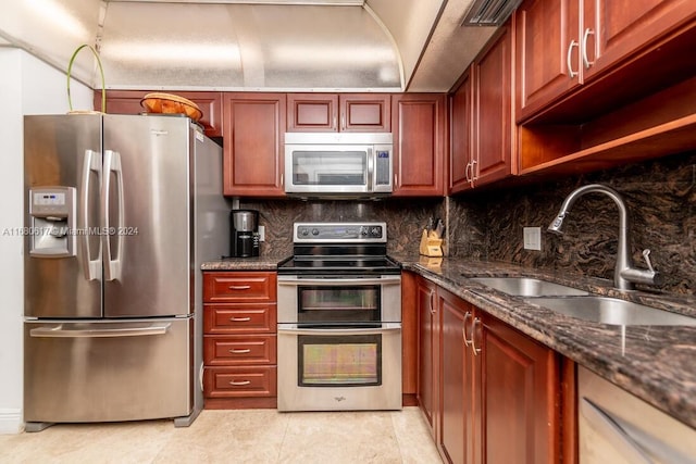 kitchen featuring backsplash, dark stone countertops, sink, light tile patterned flooring, and appliances with stainless steel finishes