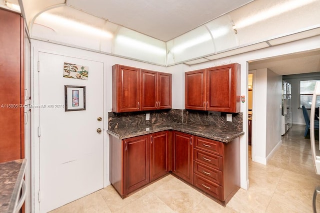 kitchen with decorative backsplash, dark stone countertops, and light tile patterned floors