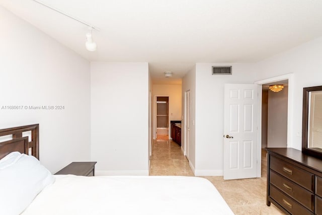 bedroom with connected bathroom and track lighting