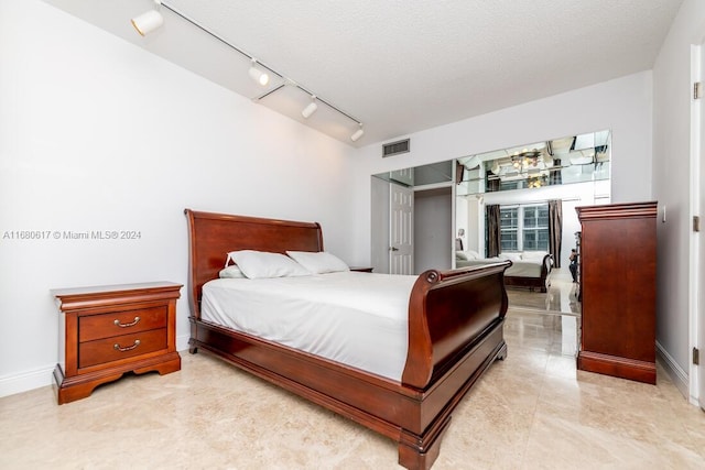 bedroom with a textured ceiling and track lighting