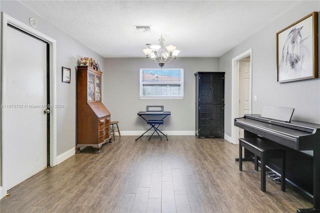 miscellaneous room with dark wood-type flooring, a textured ceiling, and an inviting chandelier