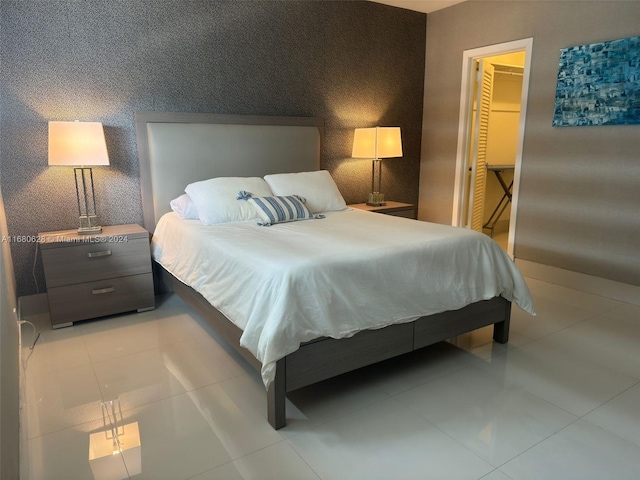 bedroom featuring a closet, light tile patterned floors, and a walk in closet