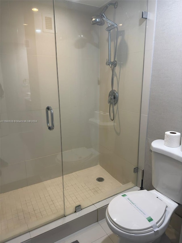 bathroom with a shower with door, toilet, and tile patterned flooring