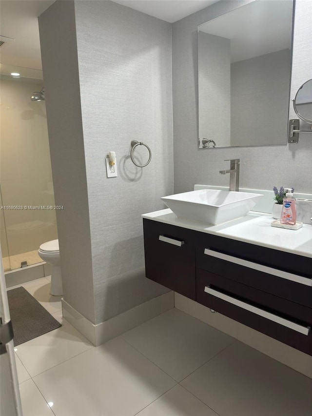 bathroom featuring toilet, vanity, a shower, and tile patterned flooring