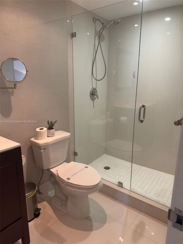 bathroom with vanity, a shower with shower door, toilet, and tile patterned floors