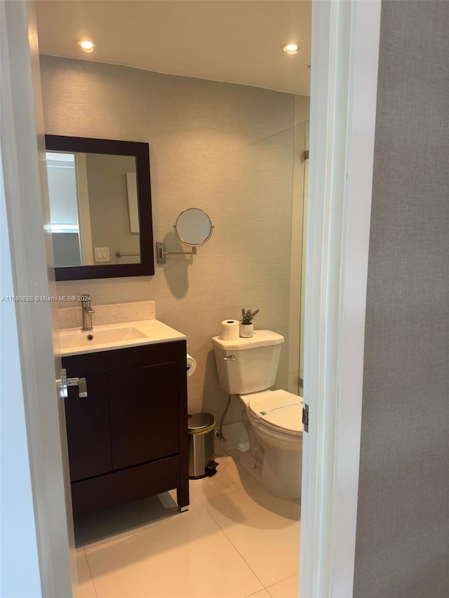 bathroom with toilet, vanity, and tile patterned flooring