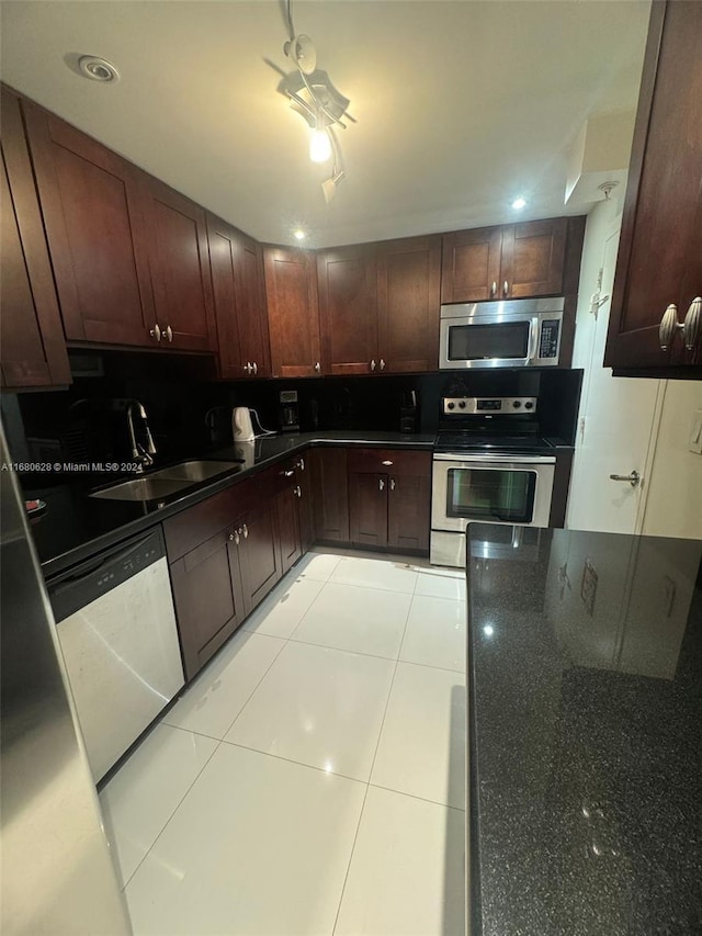 kitchen featuring decorative backsplash, light tile patterned floors, ceiling fan, sink, and stainless steel appliances