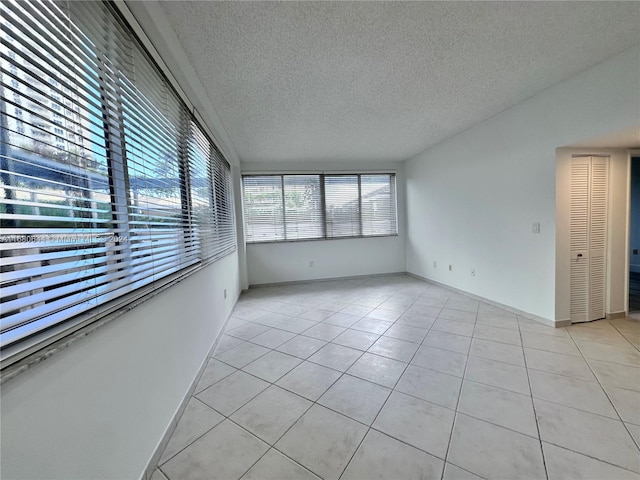 spare room with a textured ceiling and light tile patterned floors