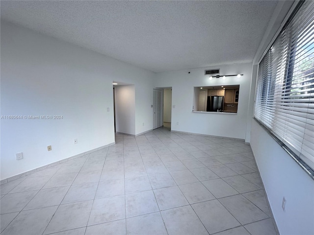 tiled spare room with a textured ceiling and ceiling fan