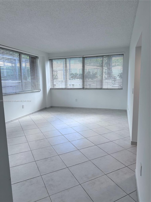 spare room featuring light tile patterned flooring, a textured ceiling, and plenty of natural light