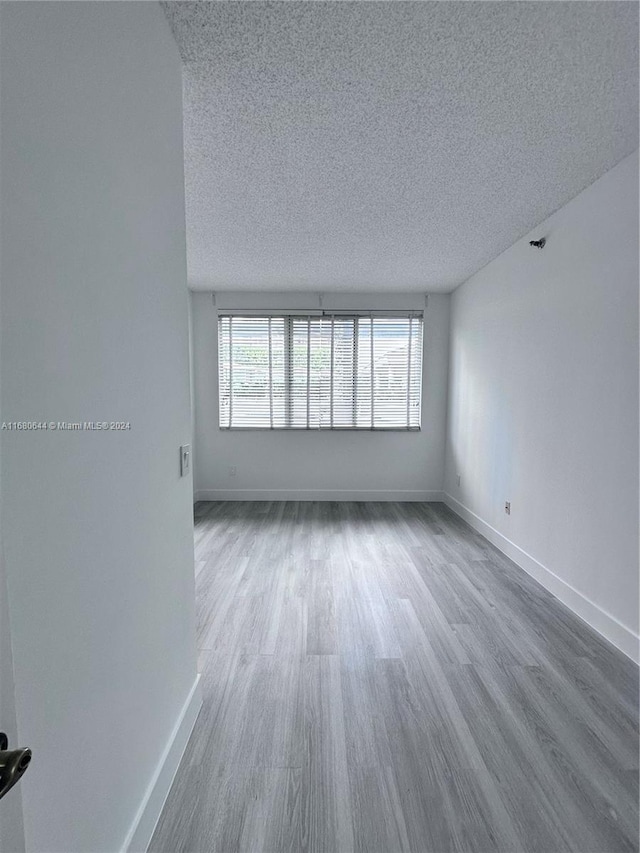 unfurnished room with a textured ceiling and hardwood / wood-style floors