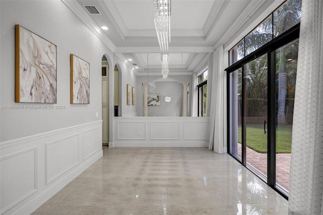 corridor with a raised ceiling, a wealth of natural light, a notable chandelier, and ornamental molding