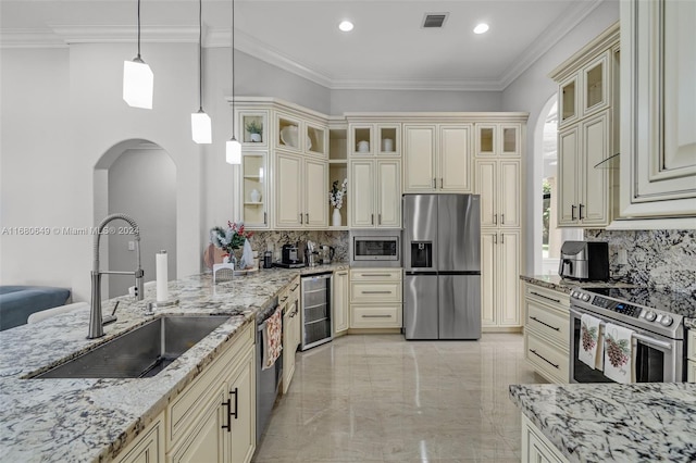 kitchen with cream cabinetry, stainless steel appliances, hanging light fixtures, and beverage cooler