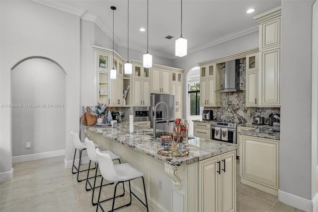 kitchen featuring decorative backsplash, cream cabinets, wall chimney exhaust hood, and pendant lighting