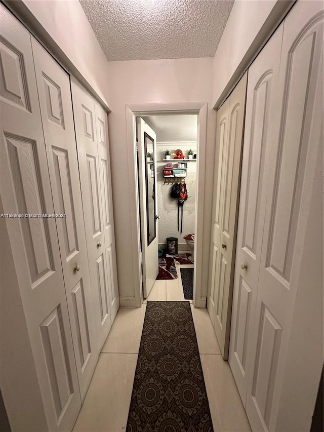 hallway featuring a textured ceiling and light tile patterned floors