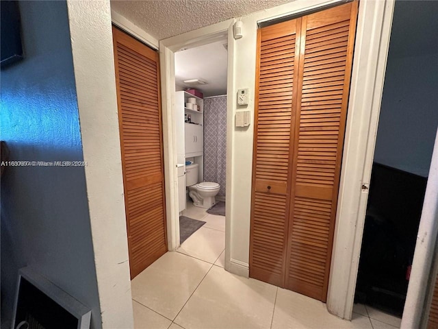 bathroom featuring a textured ceiling, toilet, and tile patterned flooring