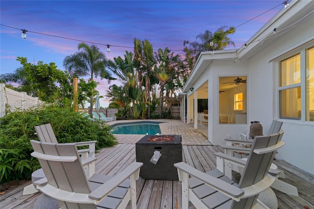 pool at dusk featuring a deck and an outdoor fire pit