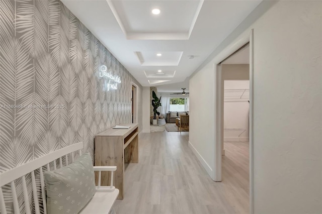 corridor featuring light wood-type flooring and a tray ceiling