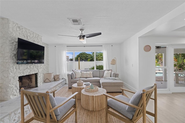 living room featuring a fireplace, light hardwood / wood-style flooring, and ceiling fan