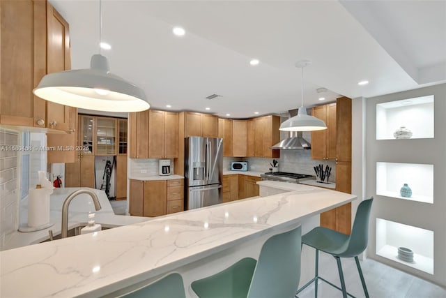 kitchen featuring light stone countertops, sink, hanging light fixtures, stainless steel refrigerator with ice dispenser, and decorative backsplash