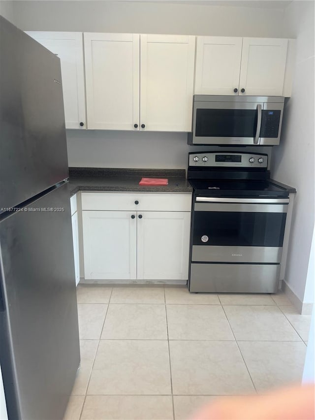 kitchen with light tile patterned floors, stainless steel appliances, and white cabinets