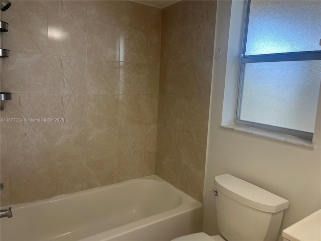 bathroom featuring tiled shower / bath combo and toilet