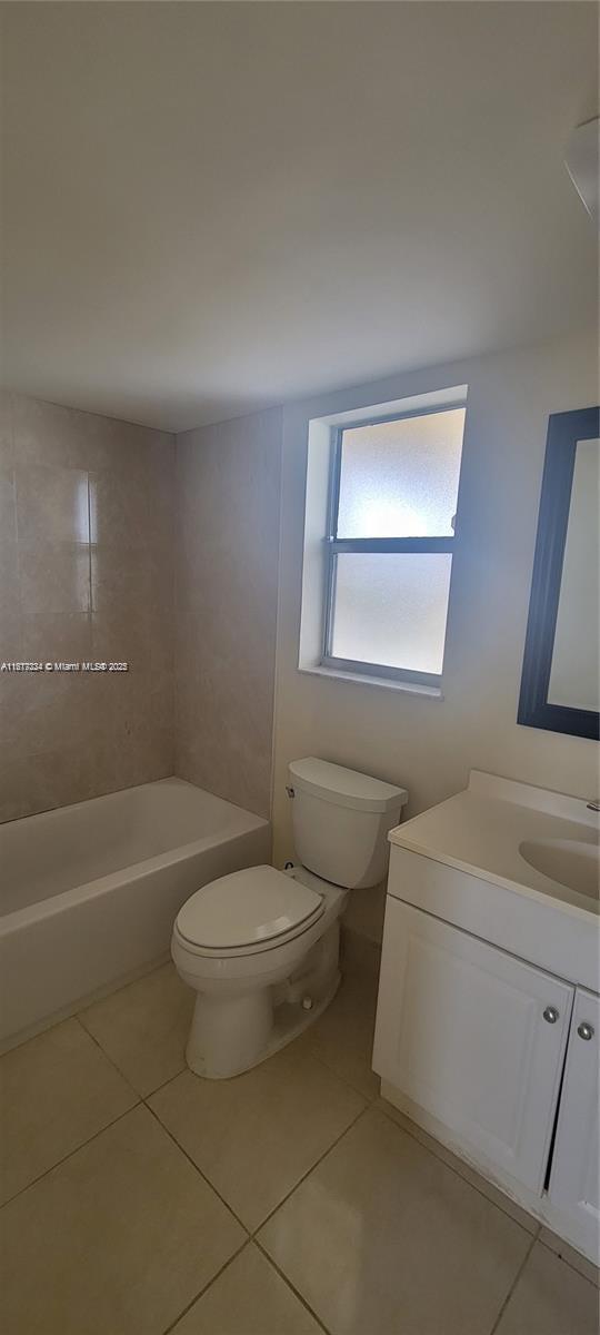 full bathroom with vanity, tiled shower / bath combo, tile patterned floors, and toilet