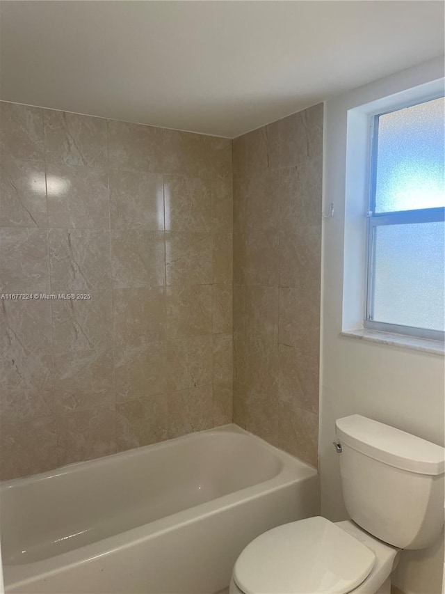 bathroom featuring tiled shower / bath and toilet