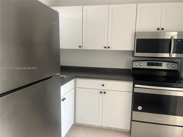 kitchen with stainless steel appliances, light tile patterned floors, and white cabinets