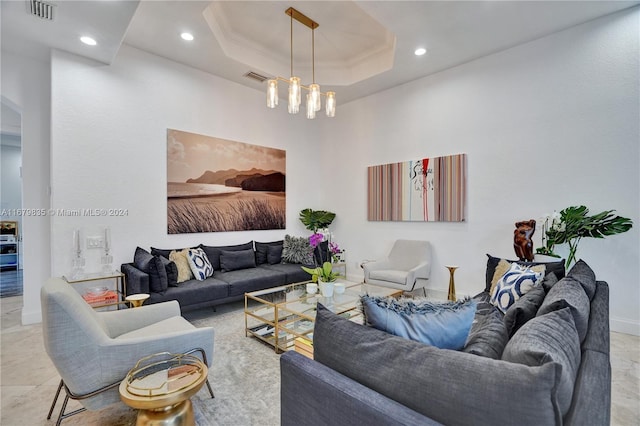 living room featuring a raised ceiling, ornamental molding, and a chandelier