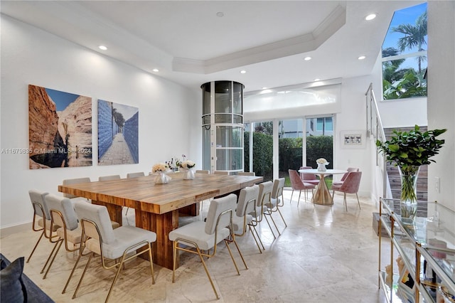 dining space with ornamental molding, a high ceiling, and a tray ceiling