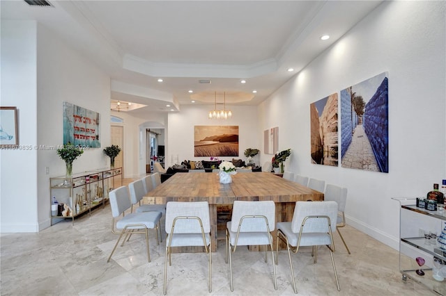 dining area featuring a raised ceiling, crown molding, and a notable chandelier