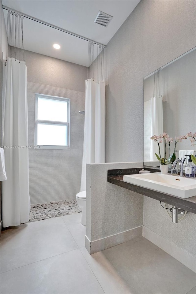 bathroom featuring tile patterned floors, toilet, walk in shower, and sink