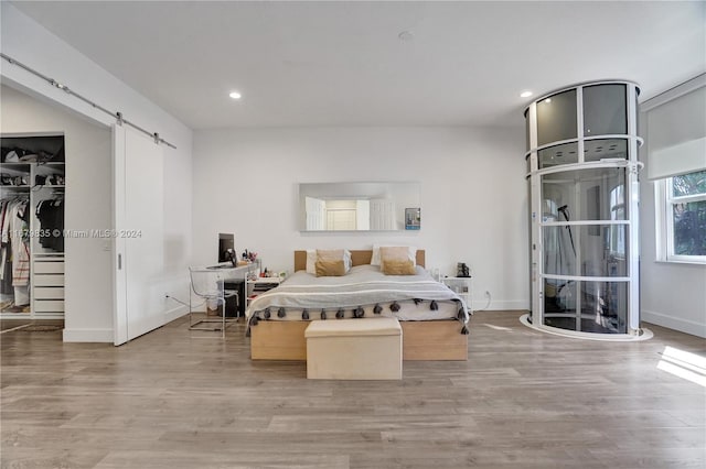 bedroom featuring a closet, a barn door, and light hardwood / wood-style flooring