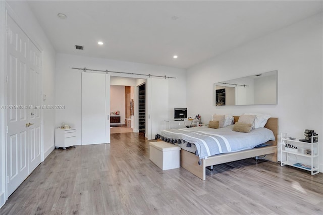 bedroom with light wood-type flooring and a barn door