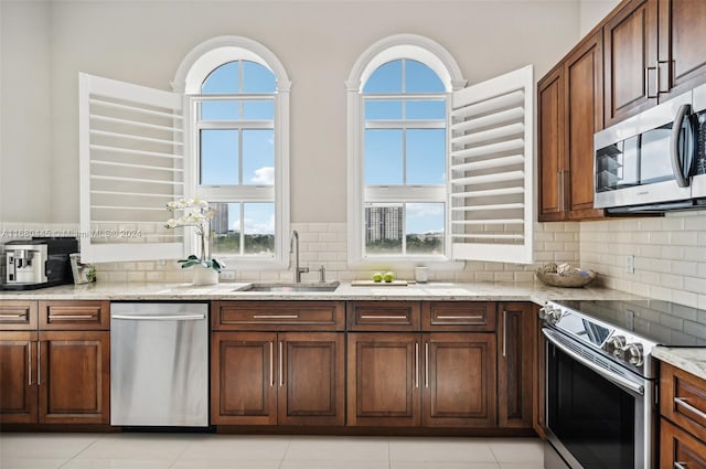 kitchen with sink, appliances with stainless steel finishes, decorative backsplash, and light tile patterned floors