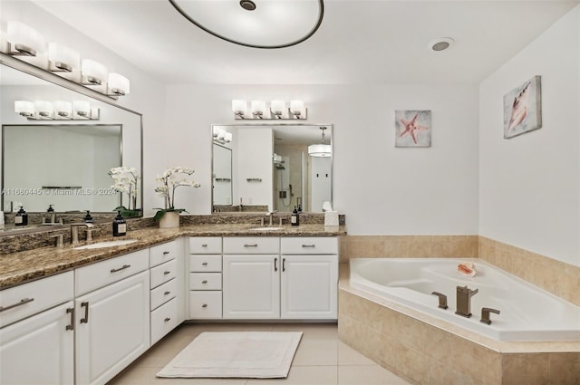 bathroom with vanity, tiled bath, and tile patterned flooring