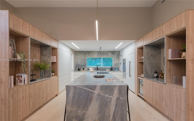 kitchen featuring decorative backsplash, dark stone countertops, light brown cabinetry, and beverage cooler