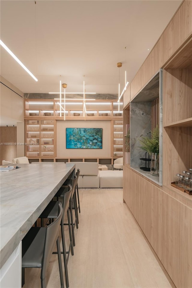 kitchen featuring light brown cabinetry, a kitchen bar, and pendant lighting